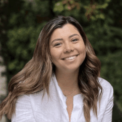 Yireth Villaverde smiling at the camera against a background of trees.